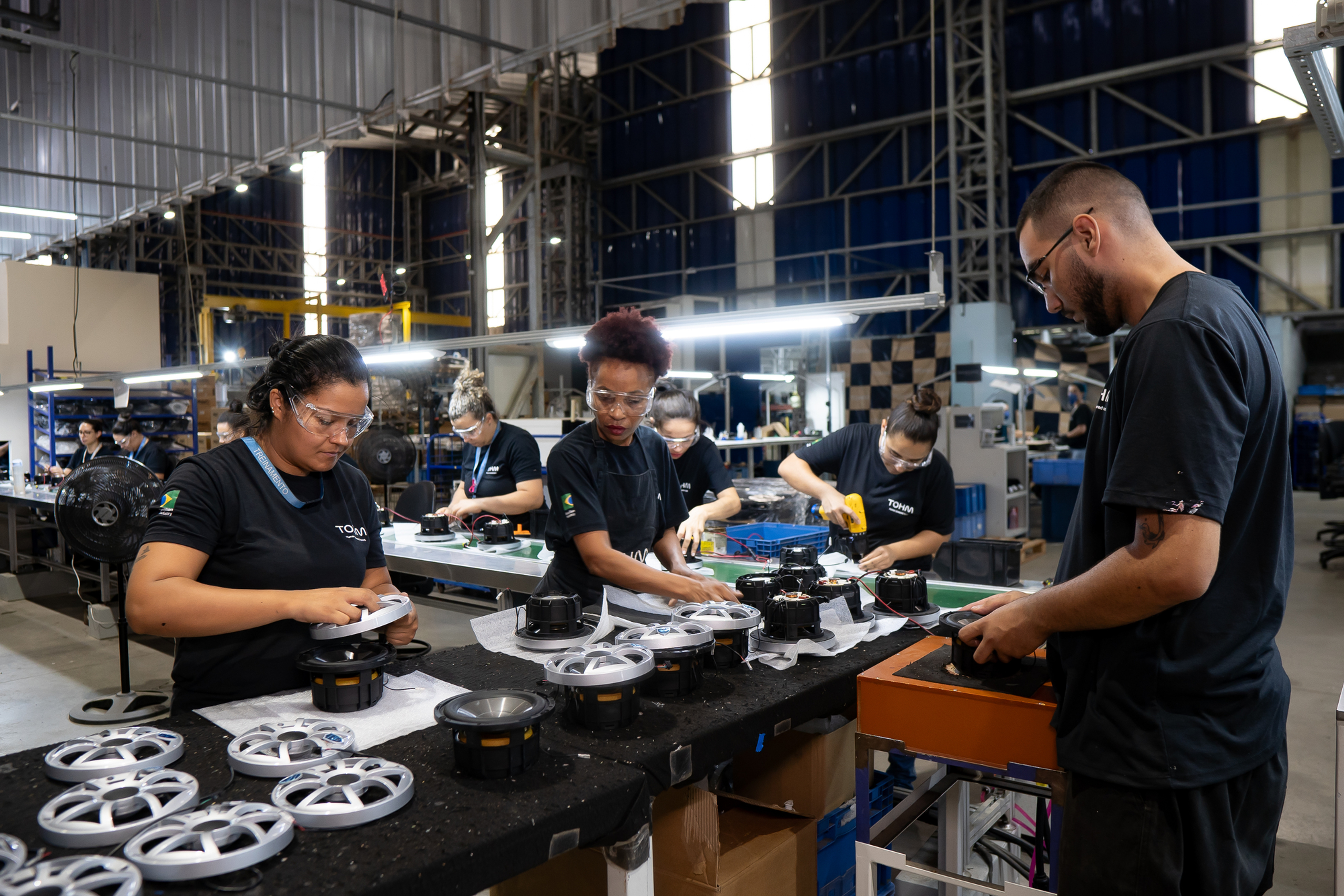 Linha de montagem manual da Tohm em Salto com a equipe operando estações de qualidade.
